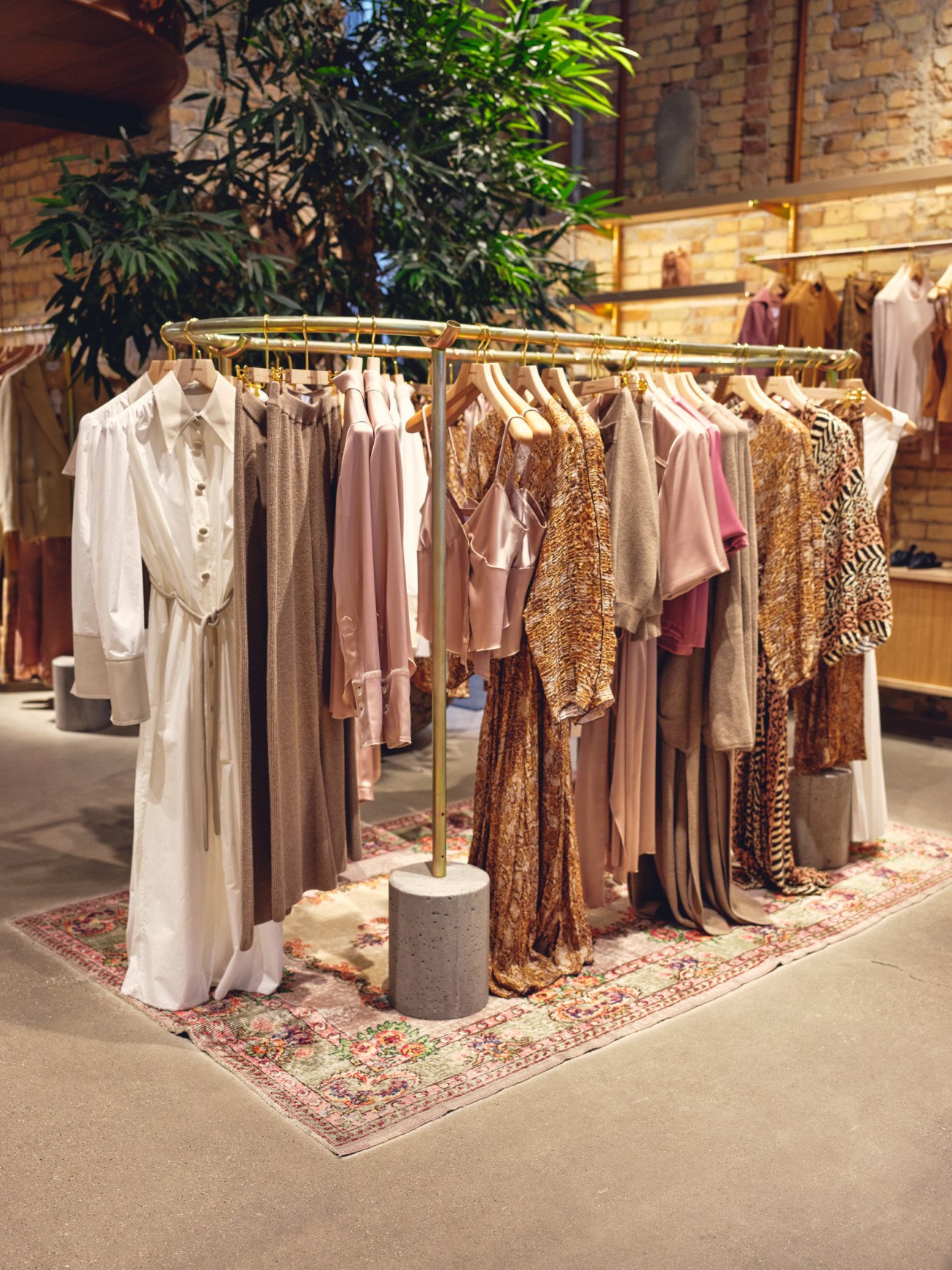 Clothing rail displaying Nanushka's collection of dresses and garments in neutral and earthy tones.