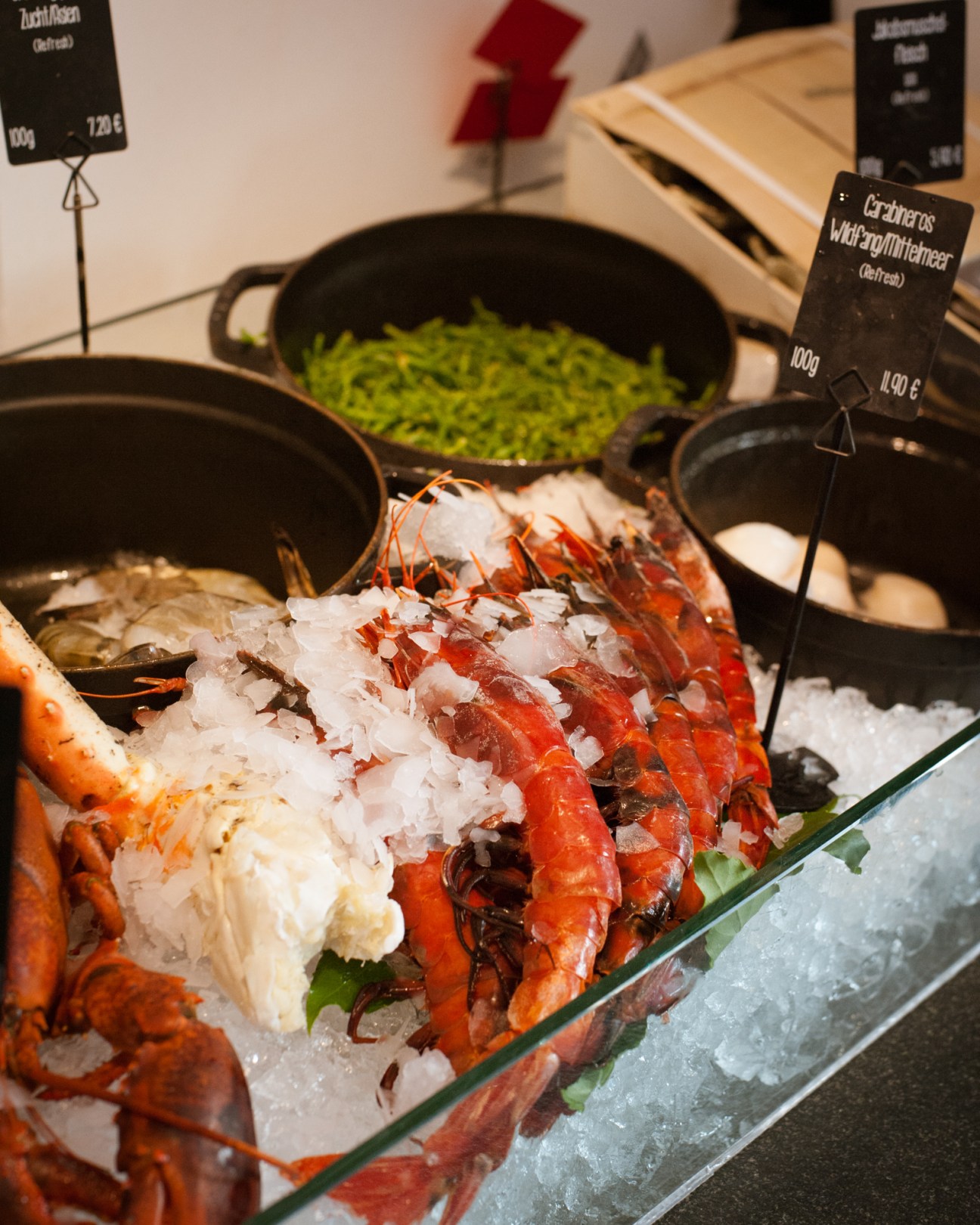 Fresh seafood display with lobster on ice at Käfer supermarket in Munich.