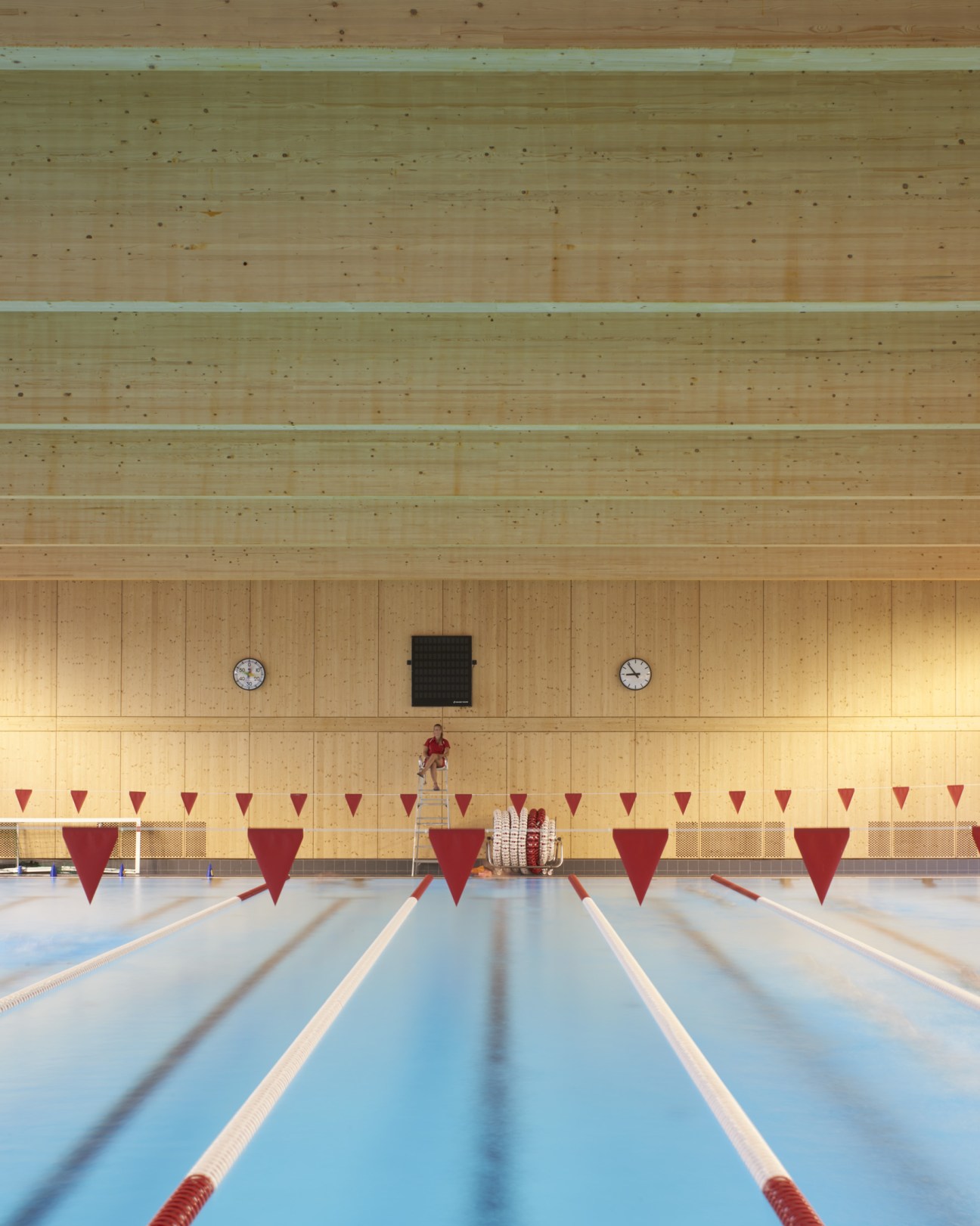 Indoor swimming pool with timber ceiling, wooden wall paneling, and floor-to-ceiling windows