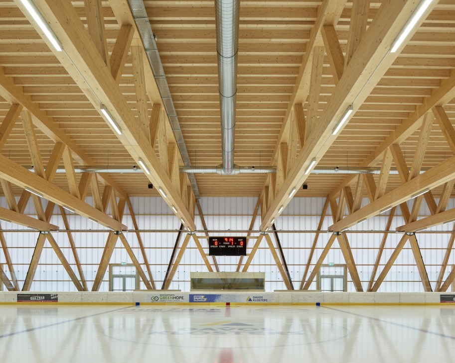 Ice hockey rink with exposed timber roof structure and geometric wooden beam framework