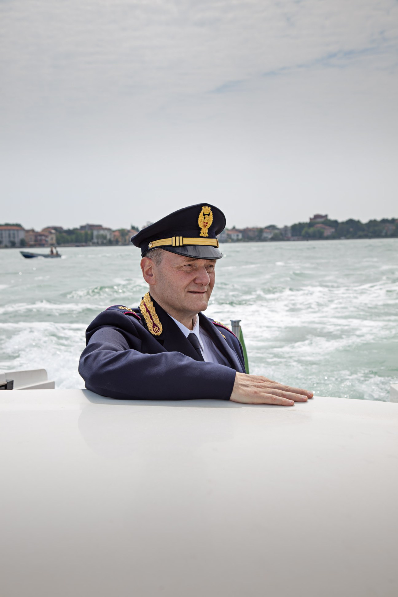Superintendent Giorgio Patara in police uniform on a boat in Venice's lagoon.