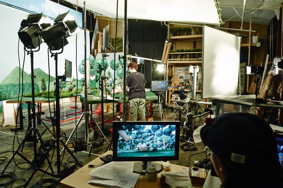 Animator Hirokazu Minegishi works at a stop-motion animation set with miniature props, lighting equipment, and monitoring screens at Dwarf studio in Tokyo.