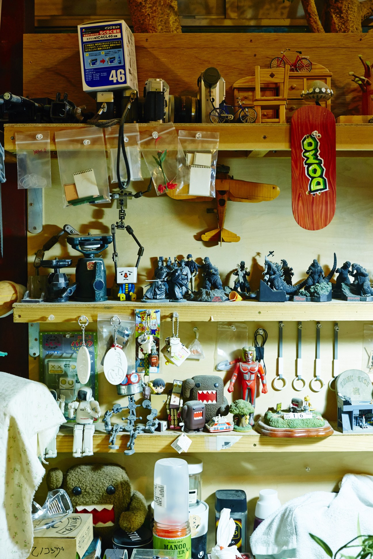 Wooden shelving unit displaying various stop-motion animation puppets, props, and miniature figures used at Dwarf studio in Tokyo.