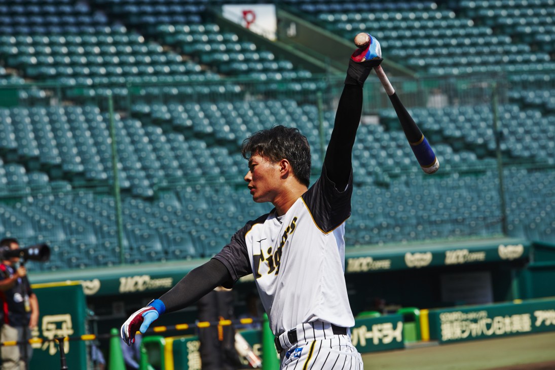 Hanshin Tigers shortstop Fumiya Hojo takes practice swings before batting at Koshien Stadium.