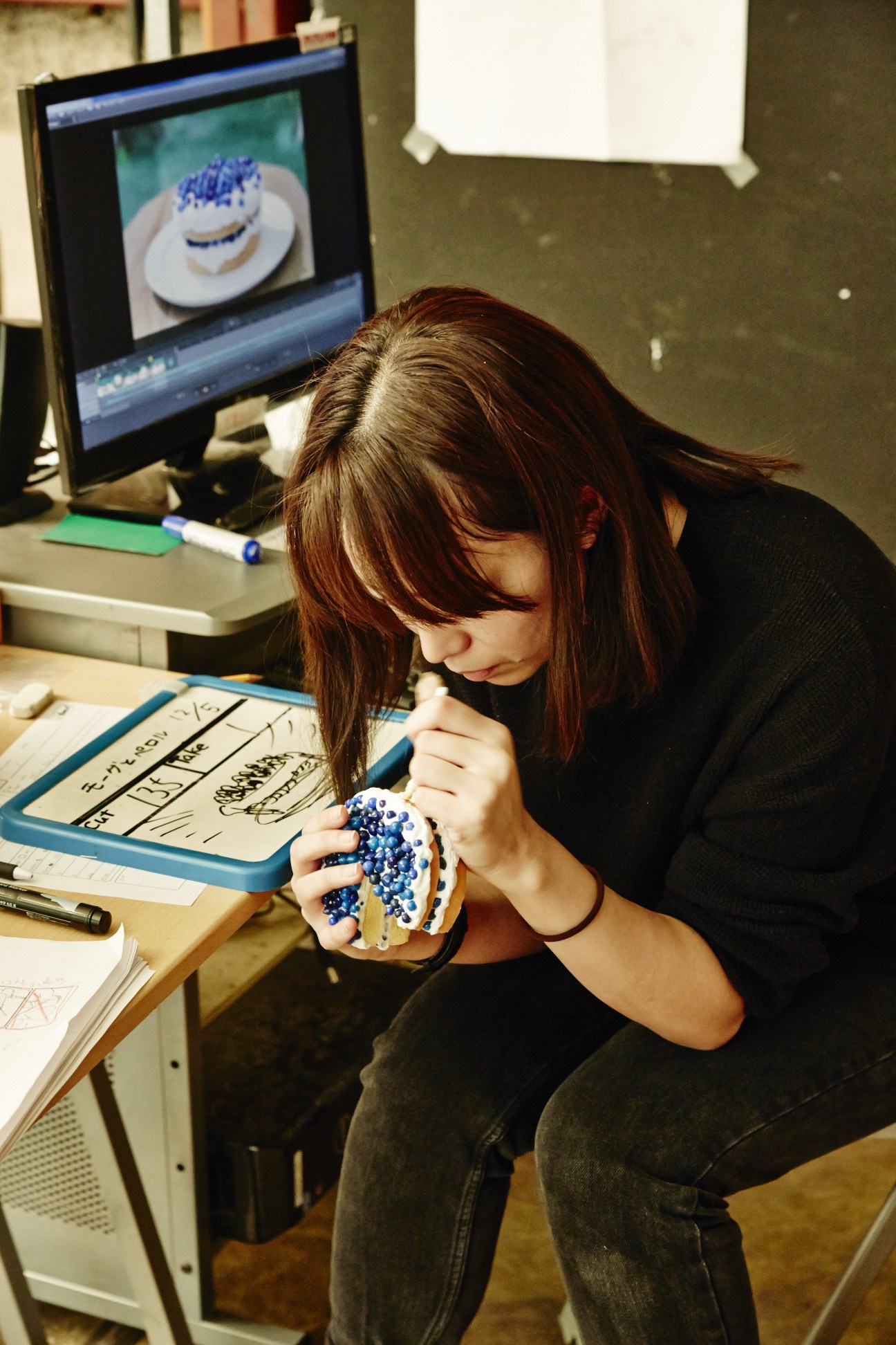 Studio animator repainting details on a miniature blue and white layered cake prop.