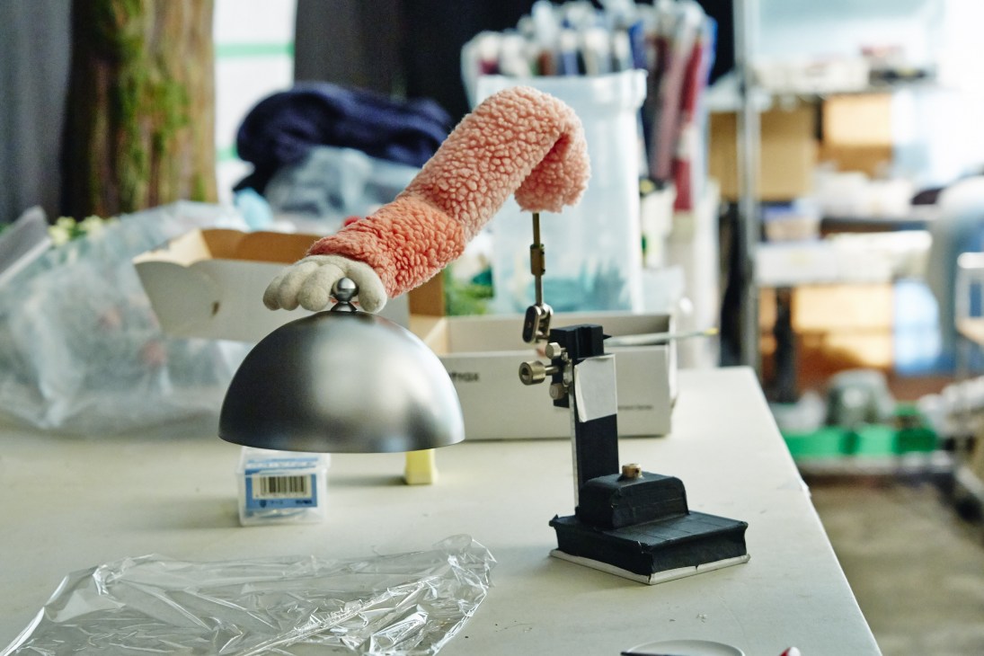 Stop-motion animation puppet with pink textured arms positioned on a work table at Dwarf studio.