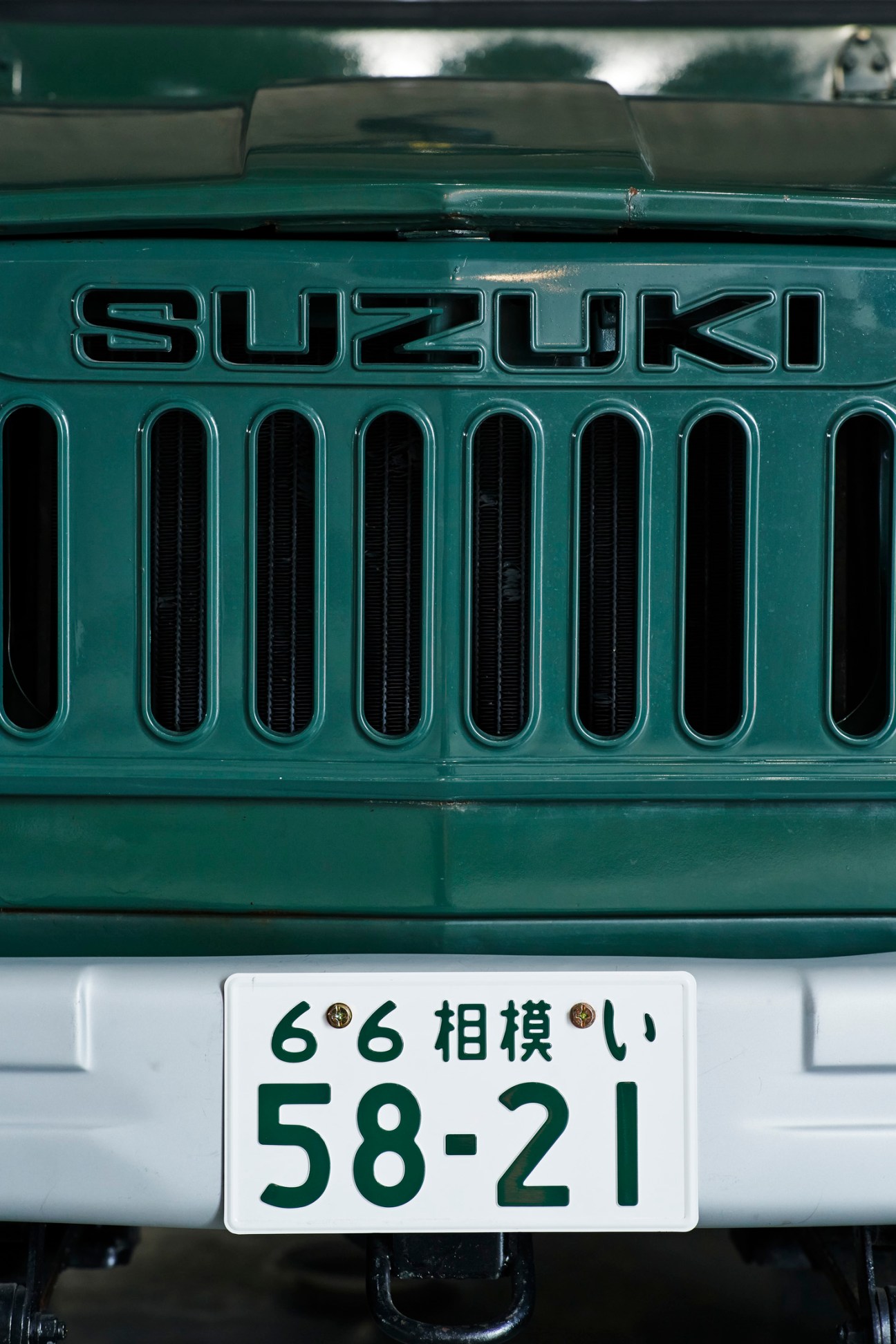 Front view of vintage green Suzuki Jimny LJ20 showing grille and Japanese license plate