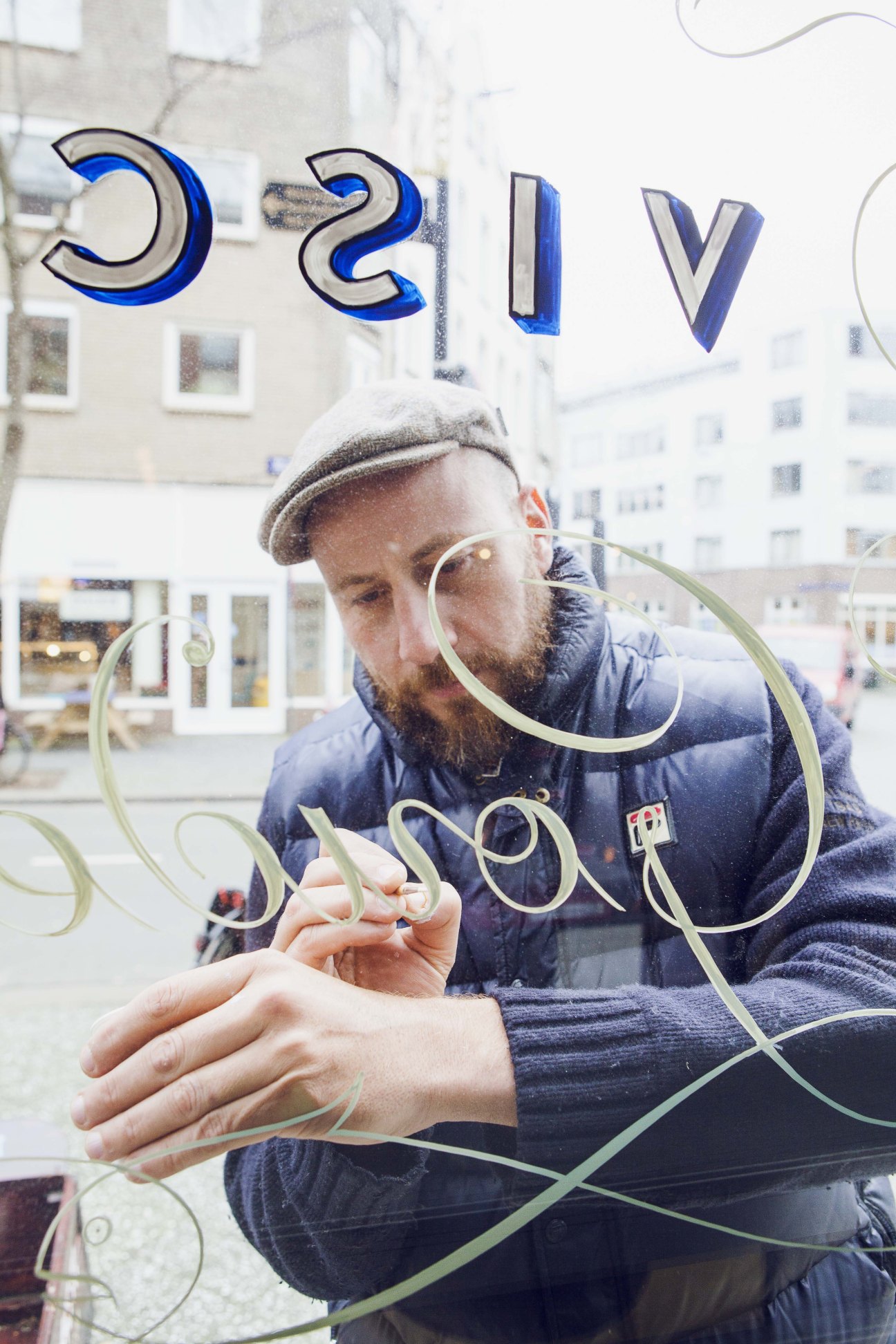 Sign painter Jasper Andries hand-painting traditional Amsterdamse Krulletter script on glass window.