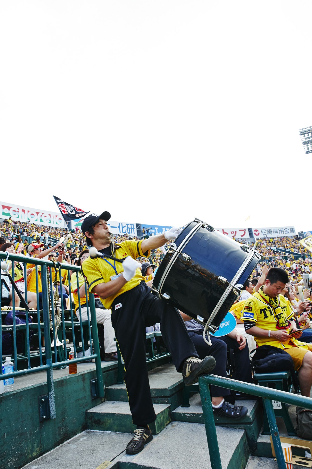 Hiroyuki Nishio, head of the Hanshin Tigers Cheering Squad, conducting fans with a drum in the stadium stands.
