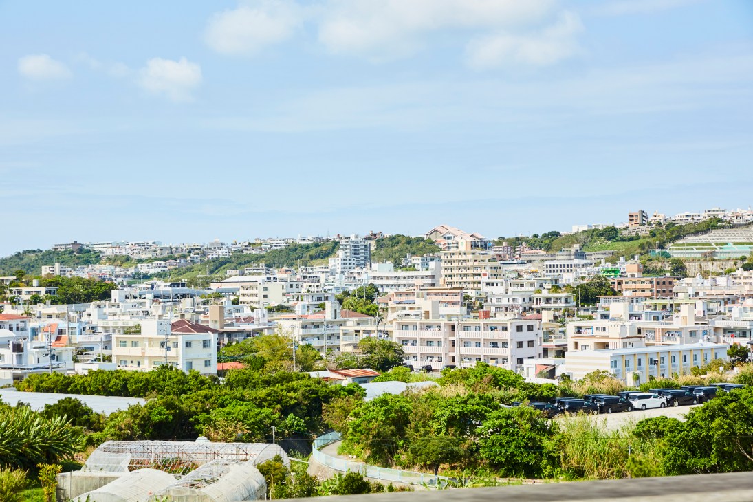 Hillside residential area with low-rise apartment buildings and lush green vegetation in Okinawa