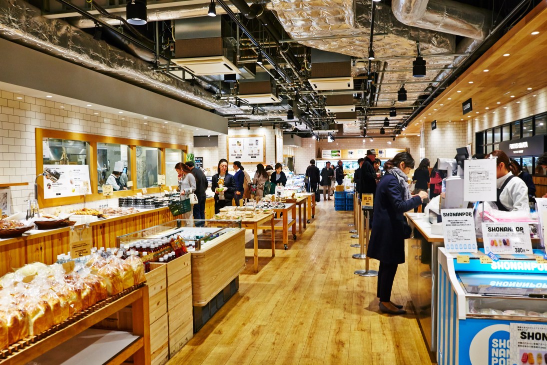 Interior of Fukushimaya supermarket with customers shopping among wooden display counters and shelving.