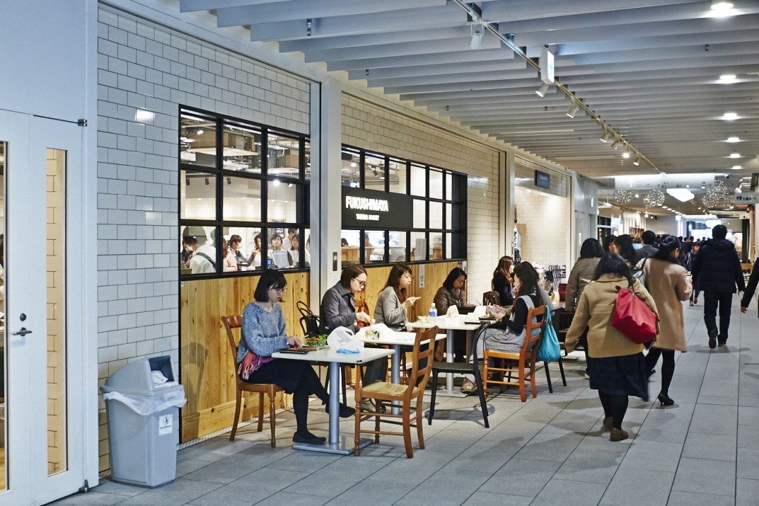 Fukushimaya Tasting Market café with customers seated at wooden tables eating meals.