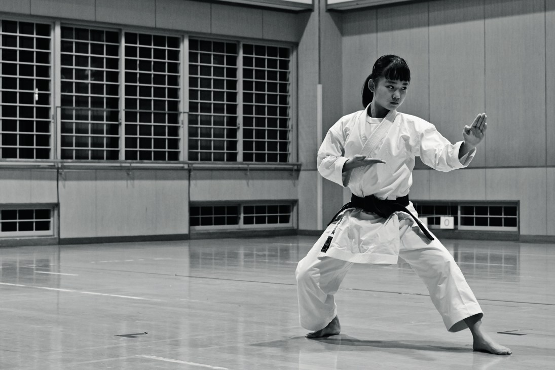 Mahiro Takano, a 13-year-old karate champion, practicing in her white karate uniform and black belt in a gymnasium