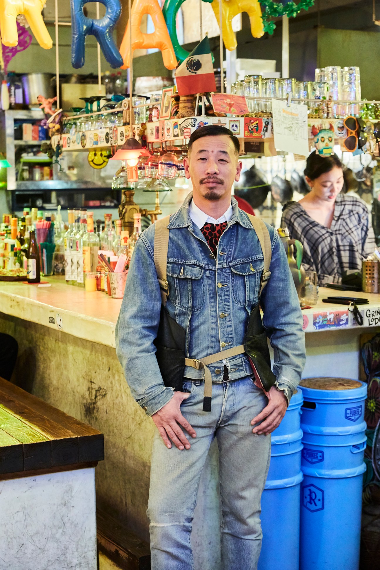 Ushio Setoguchi stands in his Mexican restaurant Borrachos wearing denim jacket and suspenders