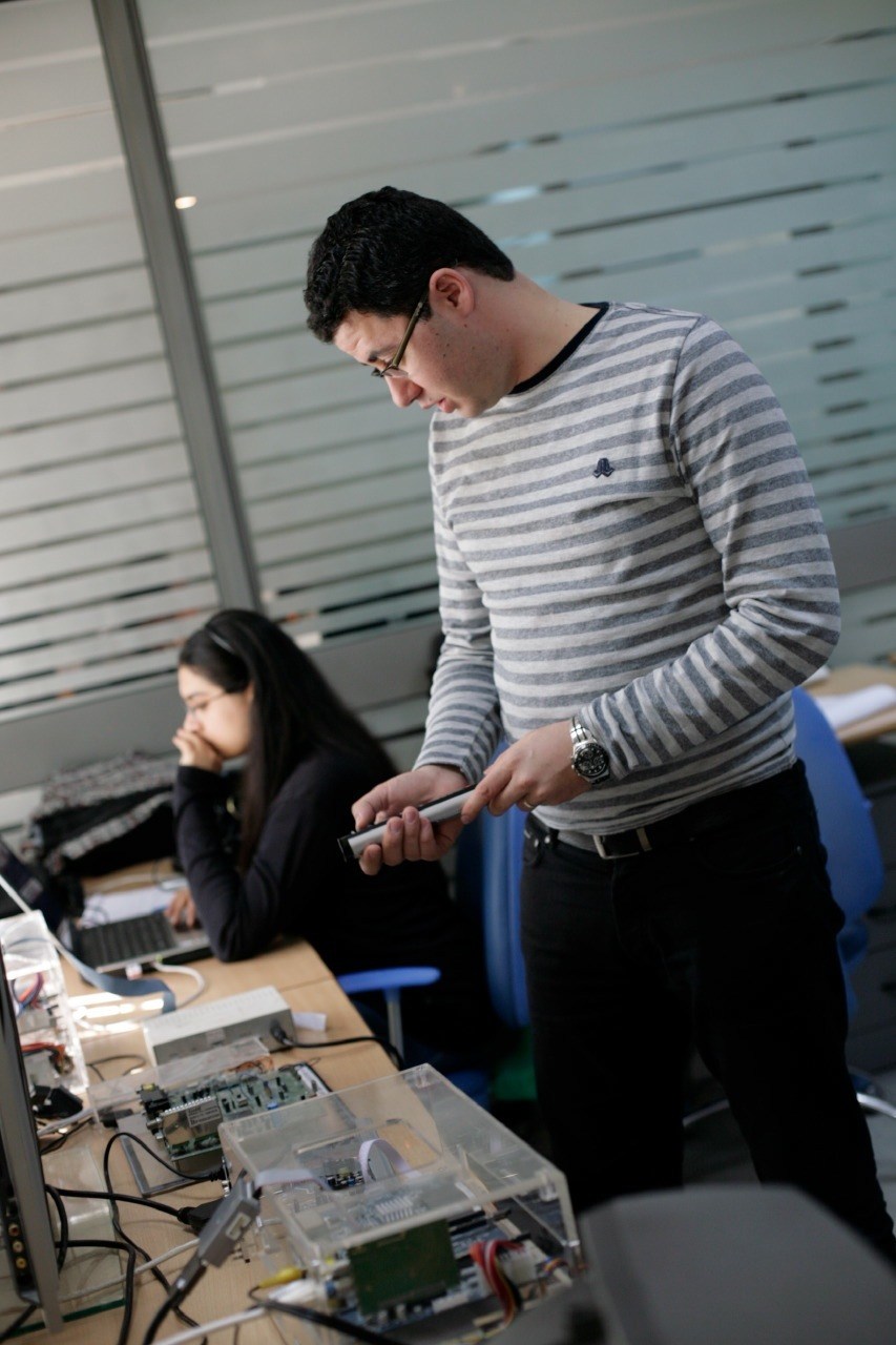 Male technician in striped shirt working with circuit boards and electronics at Telnet office.