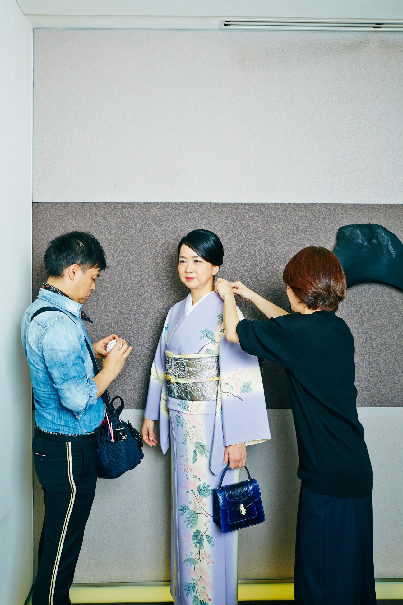 Miwako Date being prepared for a television appearance, wearing a light purple kimono with floral design and blue handbag.