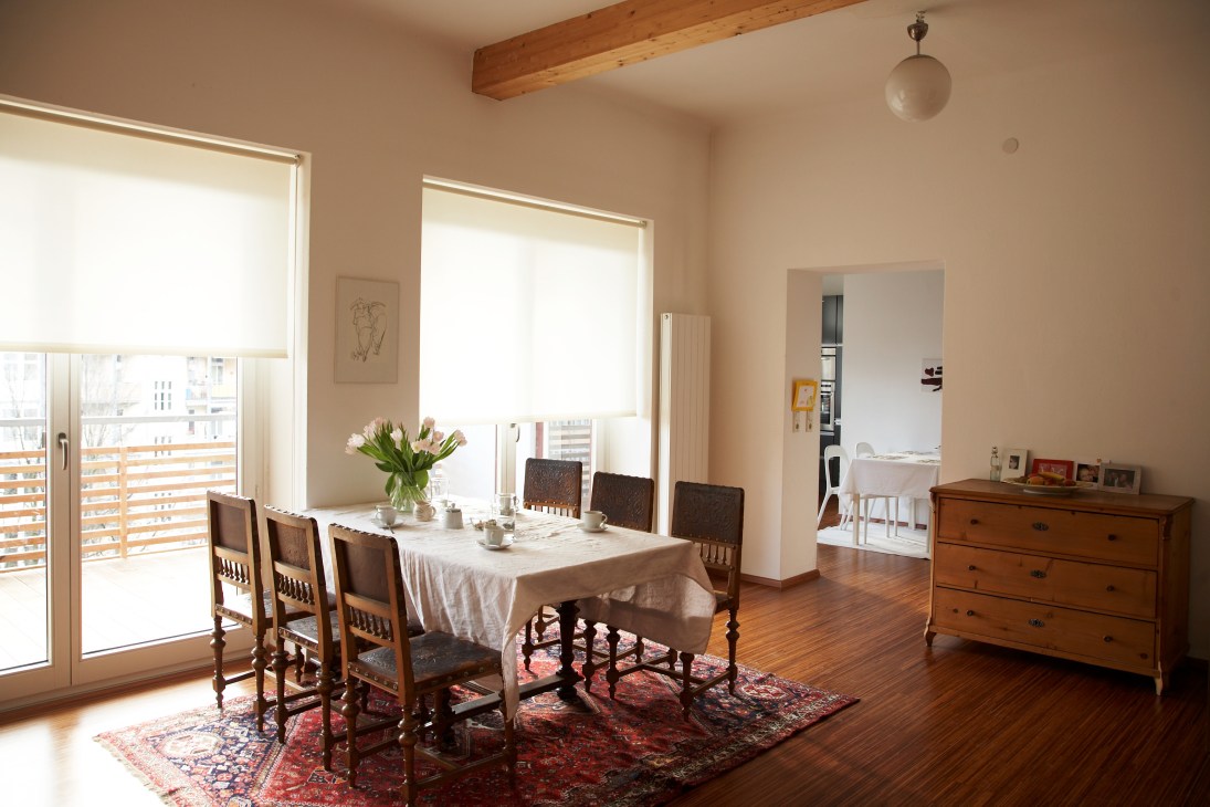 Bright dining room with wooden floor, traditional furniture, and large windows overlooking mountains.