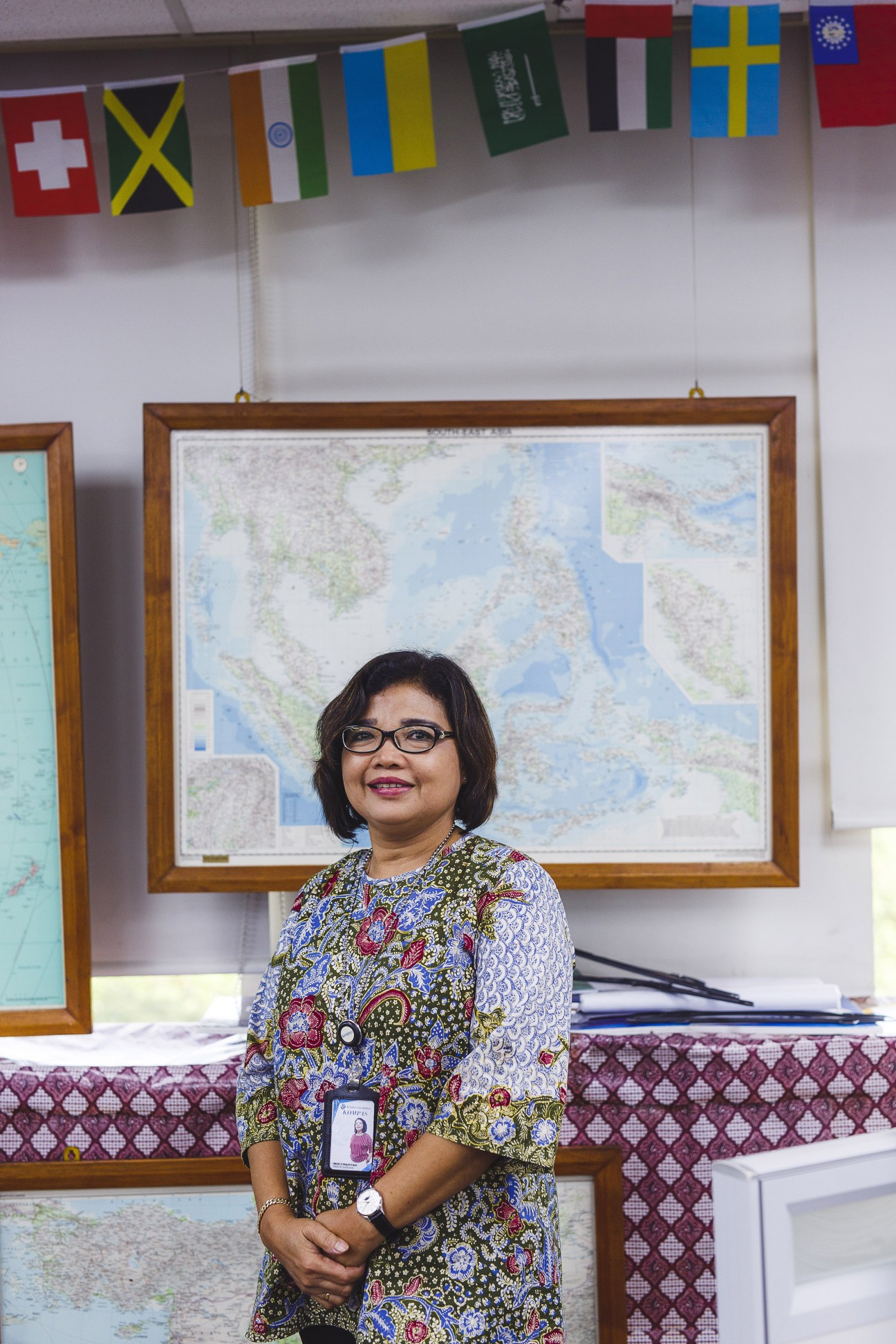 Irene Prastiyani, Kompas secretary to the chief editor, stands in an office with a framed map and international flags on the wall behind her.