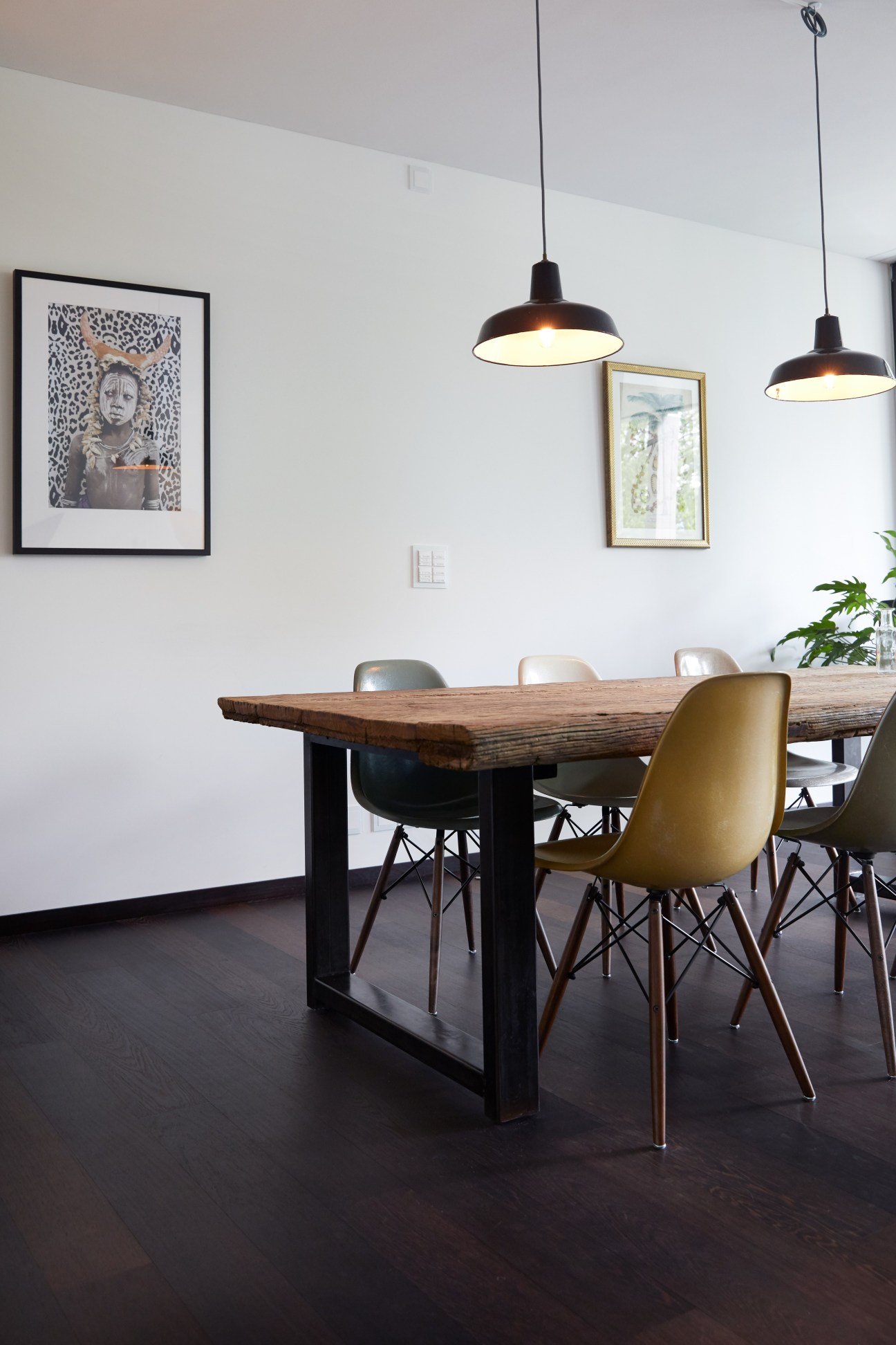 Modern dining room with wooden table, mixed seating, and black pendant lights in a converted apartment.