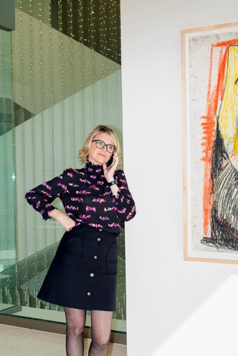 Television agent Janet Carol Norton stands in her Century City office wearing a patterned purple sweater and black skirt.