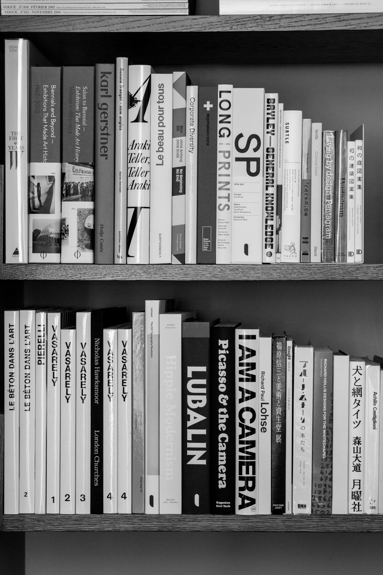 Black and white photograph of organized bookshelves displaying various books and publications