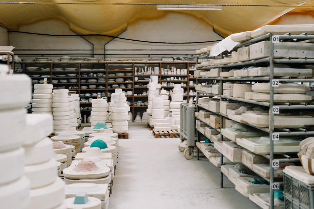 Bordallo Pinheiro factory with white ceramic pieces stacked on shelves and racks, ready for firing.