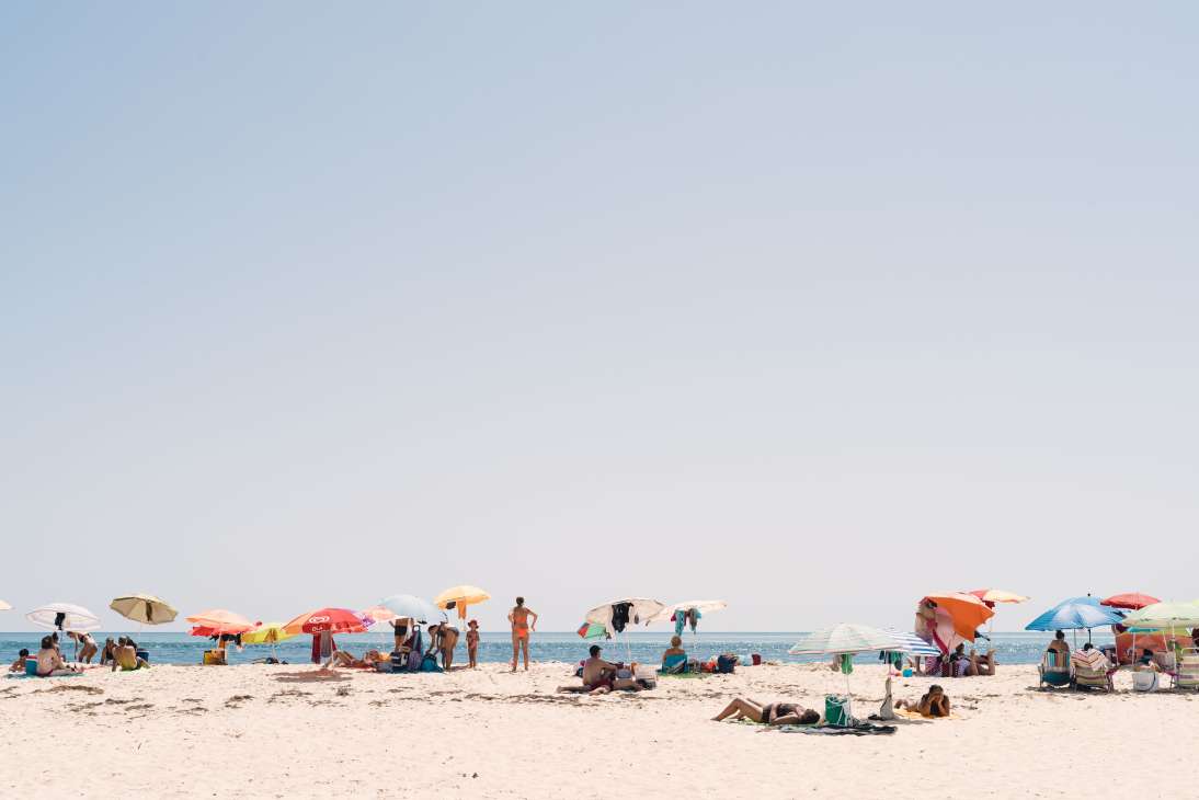 Beachgoers with colorful umbrellas relax on the sandy shore at Armona Island.