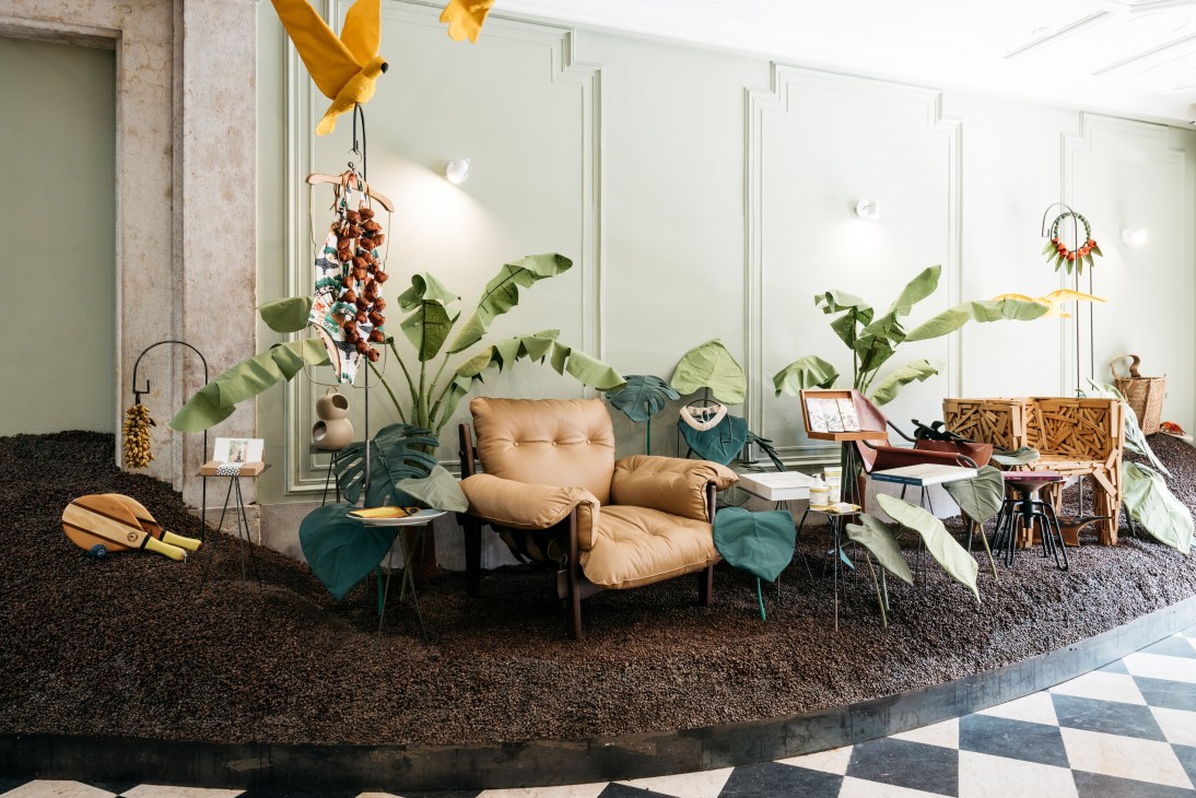 A tan leather chair surrounded by tropical plants and Brazilian design objects in Casa Pau-Brasil shop.