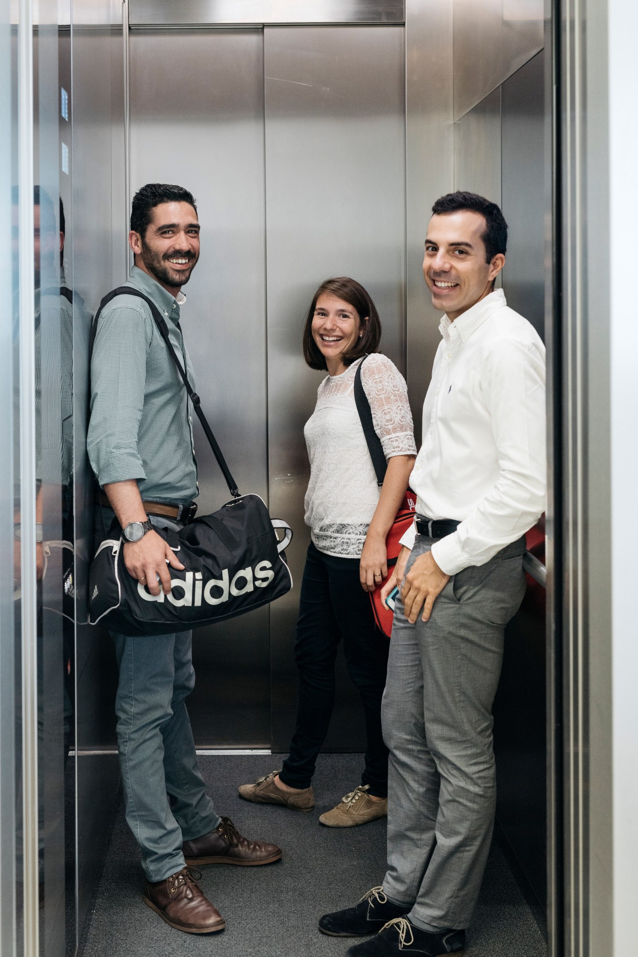 Three EDP employees in an elevator, smiling at the camera during a lunchtime break.