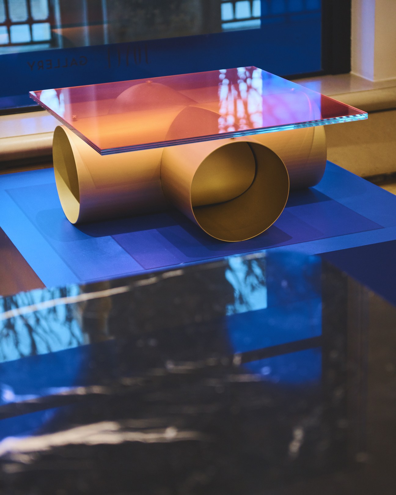 Modern metalwork table by Atelier François Pouenat with cylindrical bronze base and colorful glass top