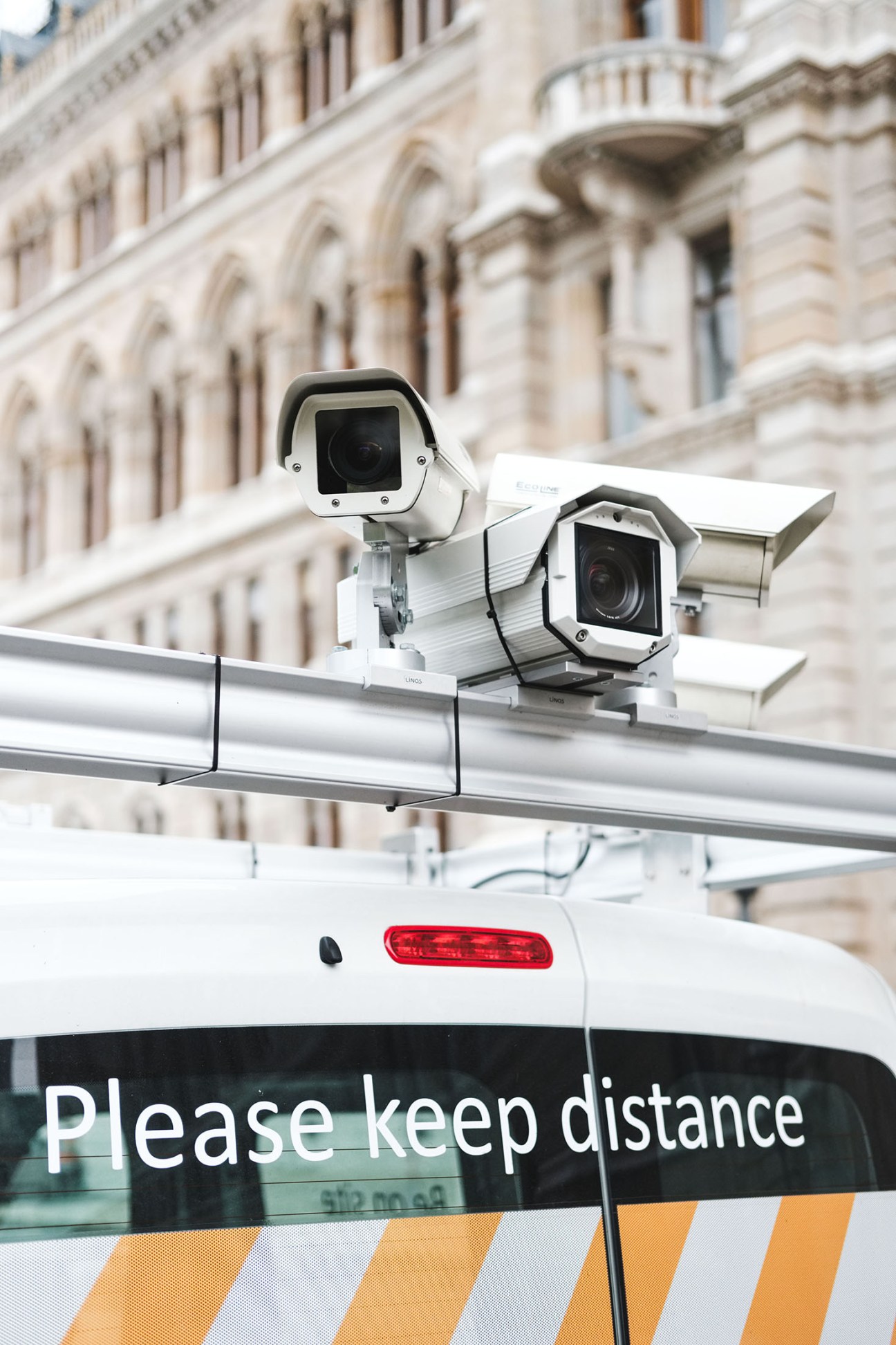Close-up of two white surveillance cameras mounted on a silver rail atop a vehicle in Vienna.