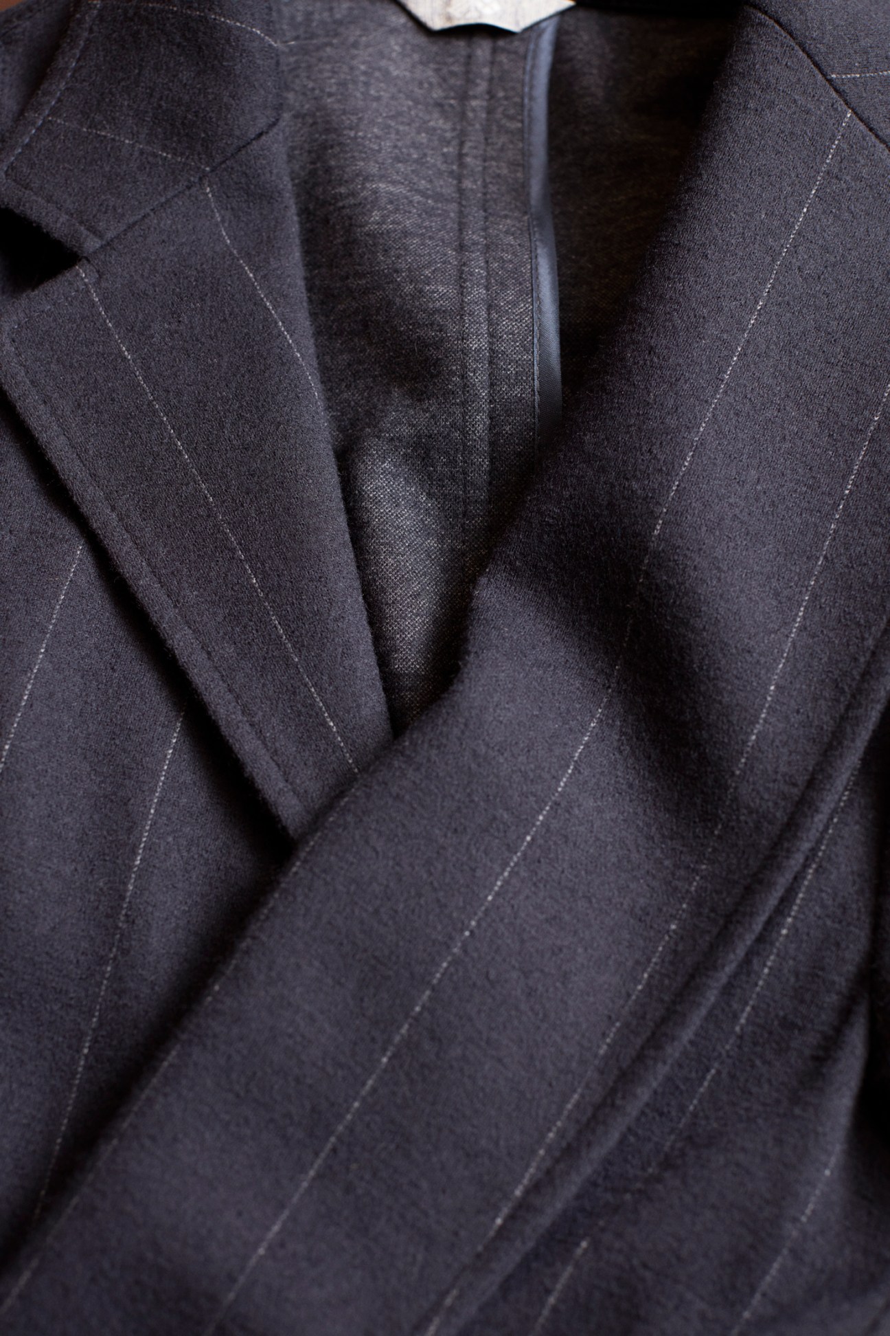 Close-up detail of a navy blazer showing tailored darts and stitching on the jacket front.