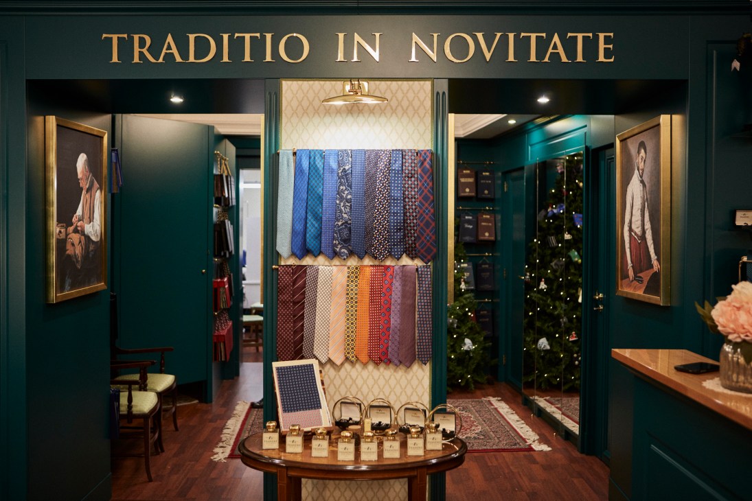 Interior of Frandré Sartoria tailoring shop with teal walls, displayed fabric swatches and ties.