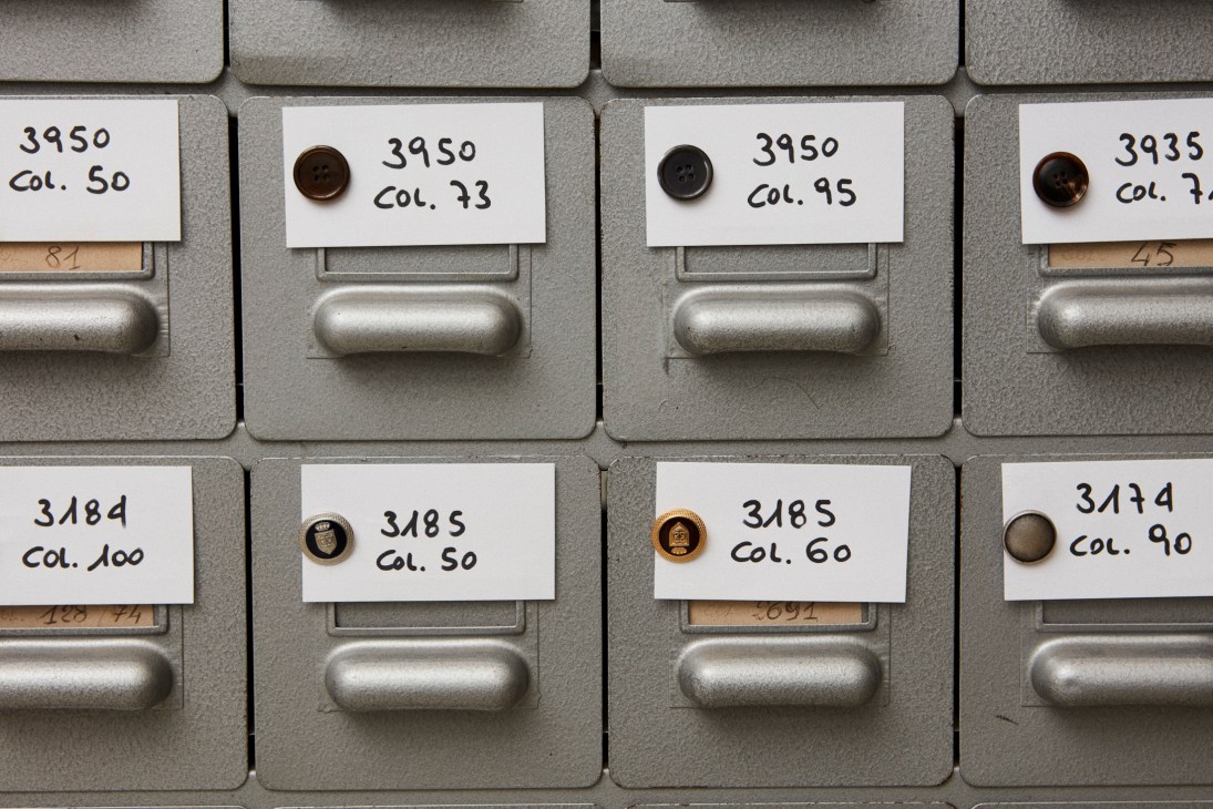 Organized button samples in labeled drawers with various brown and dark colored buttons.