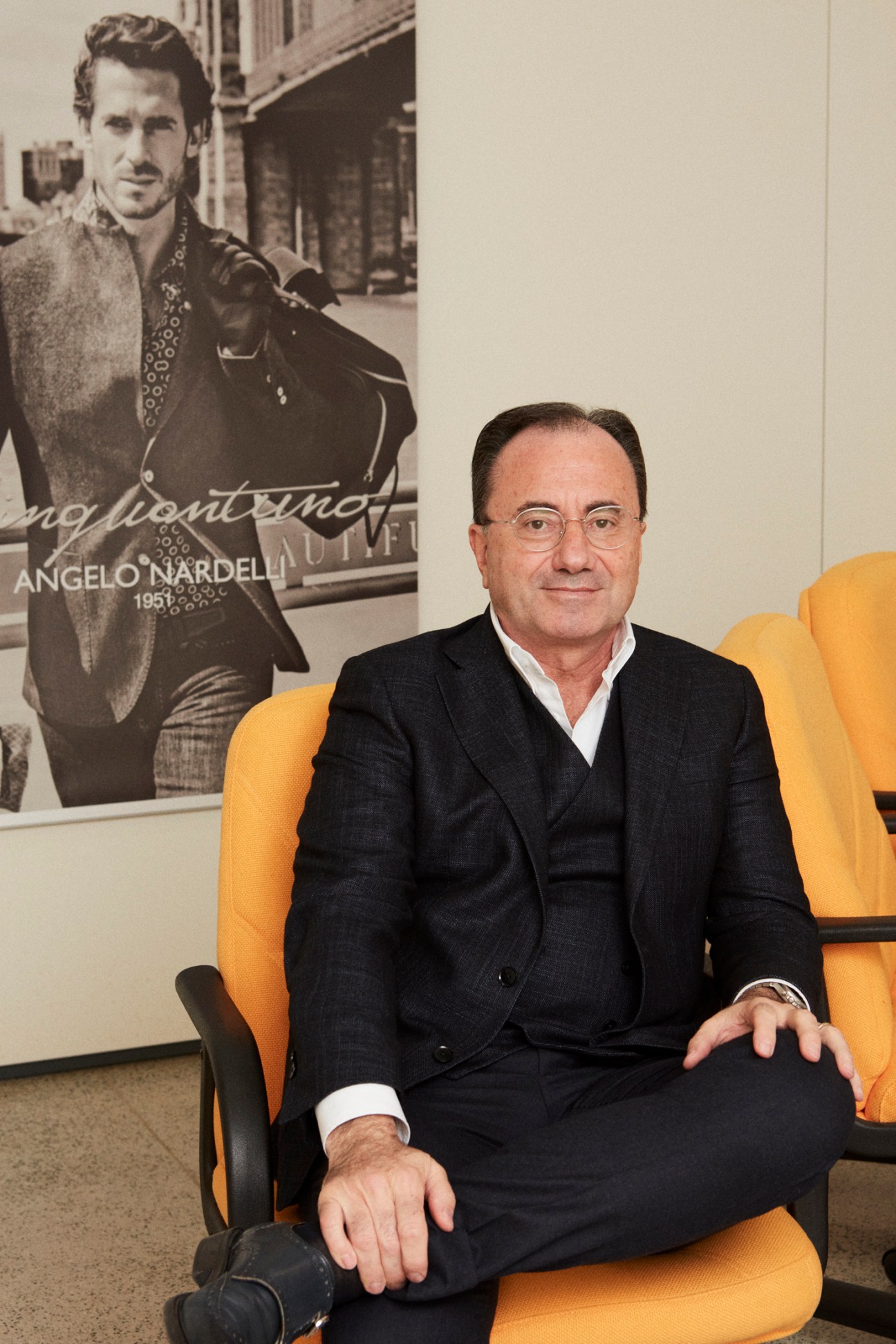 Domenico Nardelli, CEO of Angelo Nardelli, sits on a yellow chair in front of a black and white photograph of his father from 1951.
