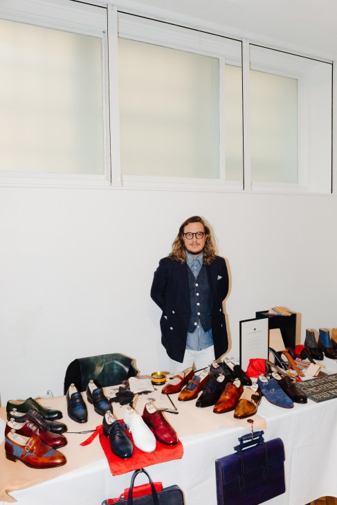 Yuya Hasegawa stands behind a display table showcasing shoes and accessories for the World Championships in Shoe Shining.