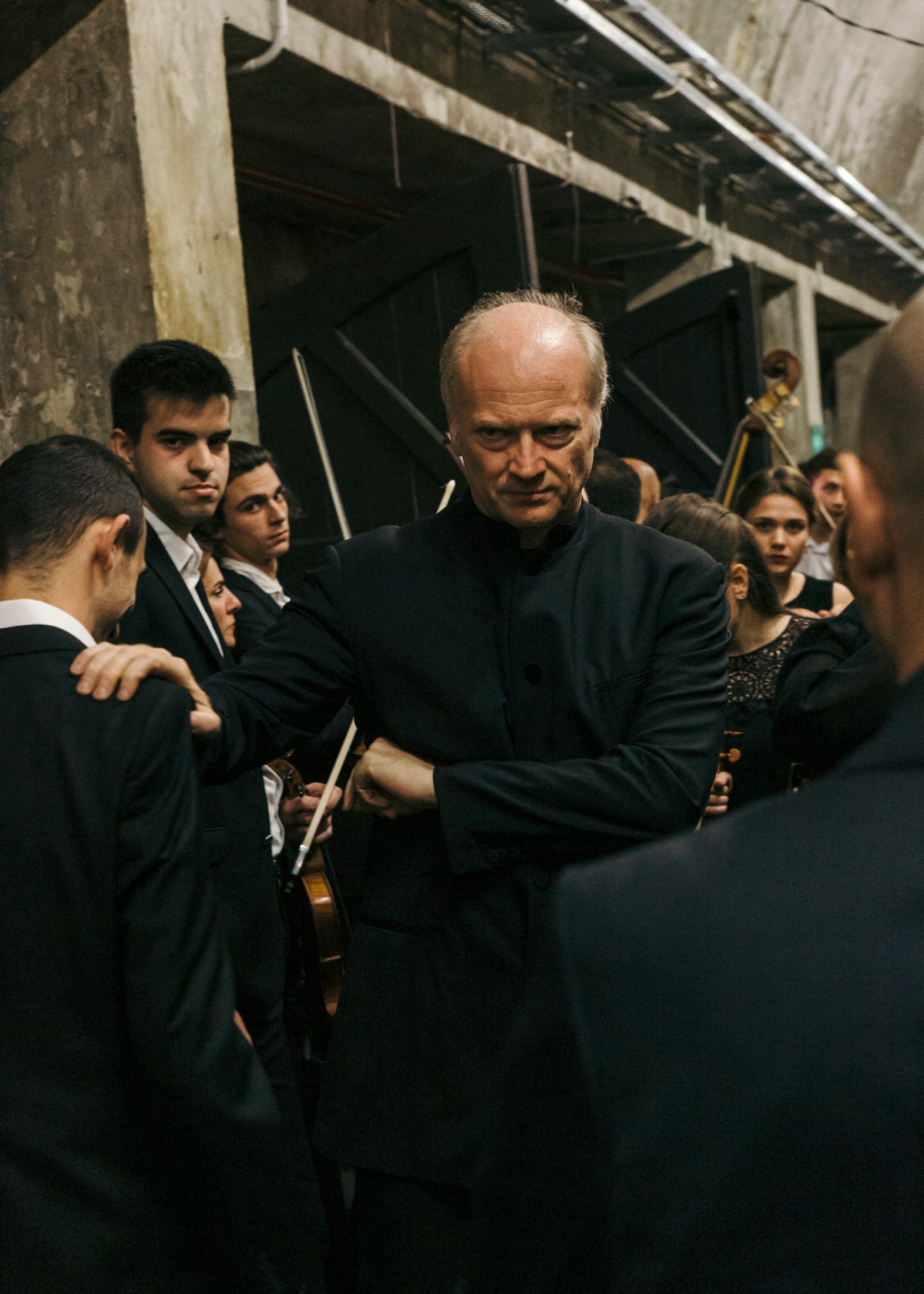Conductor Gianandrea Noseda commands attention backstage with young orchestra musicians in formal attire.