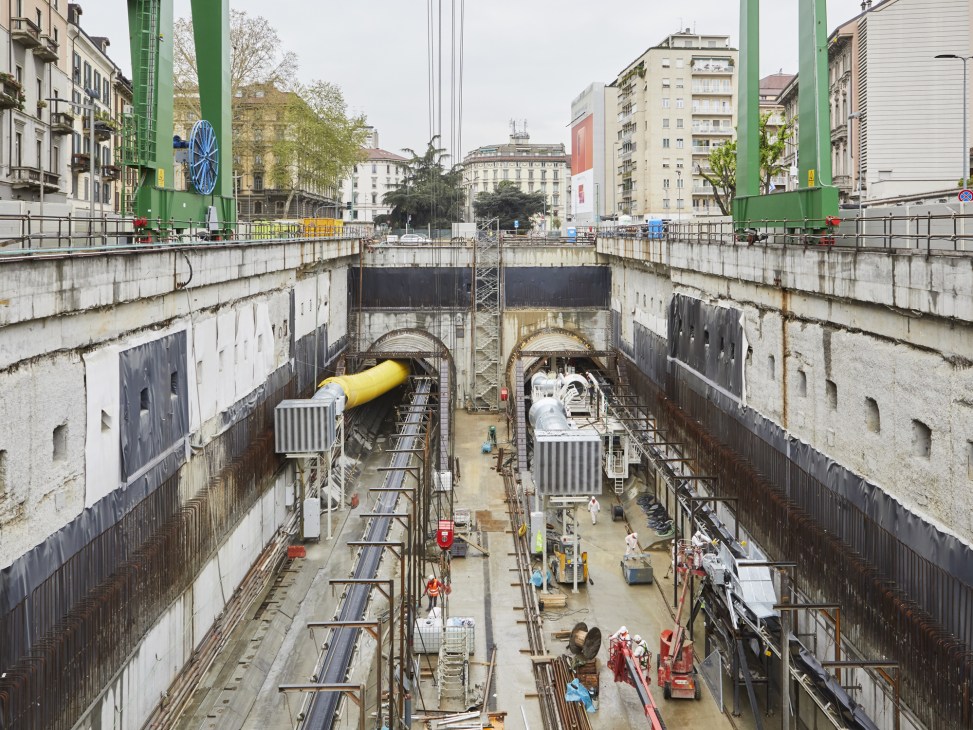 Underground metro tunnel construction site in Milan with Herrenknecht boring machines and railway tracks.