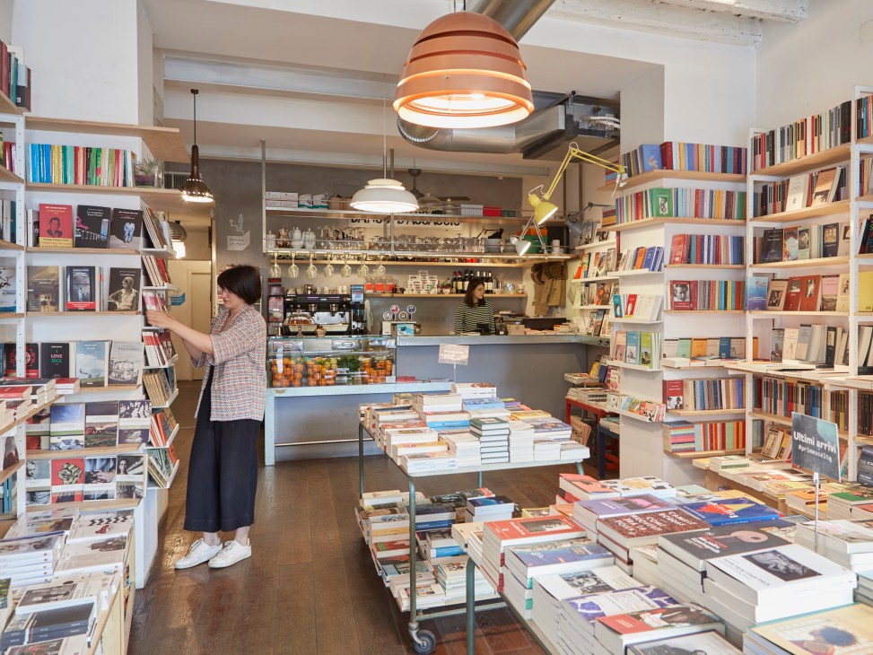 Interior of bookshop Verso in Milan showing bookshelves, a coffee counter, and a customer browsing