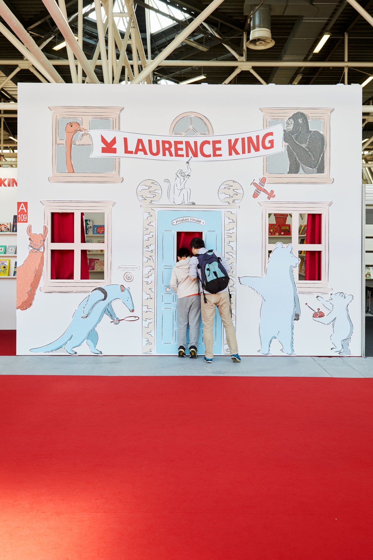 Visitor at Laurence King publisher's booth at Bologna Children's Book Fair with illustrated storefront display.