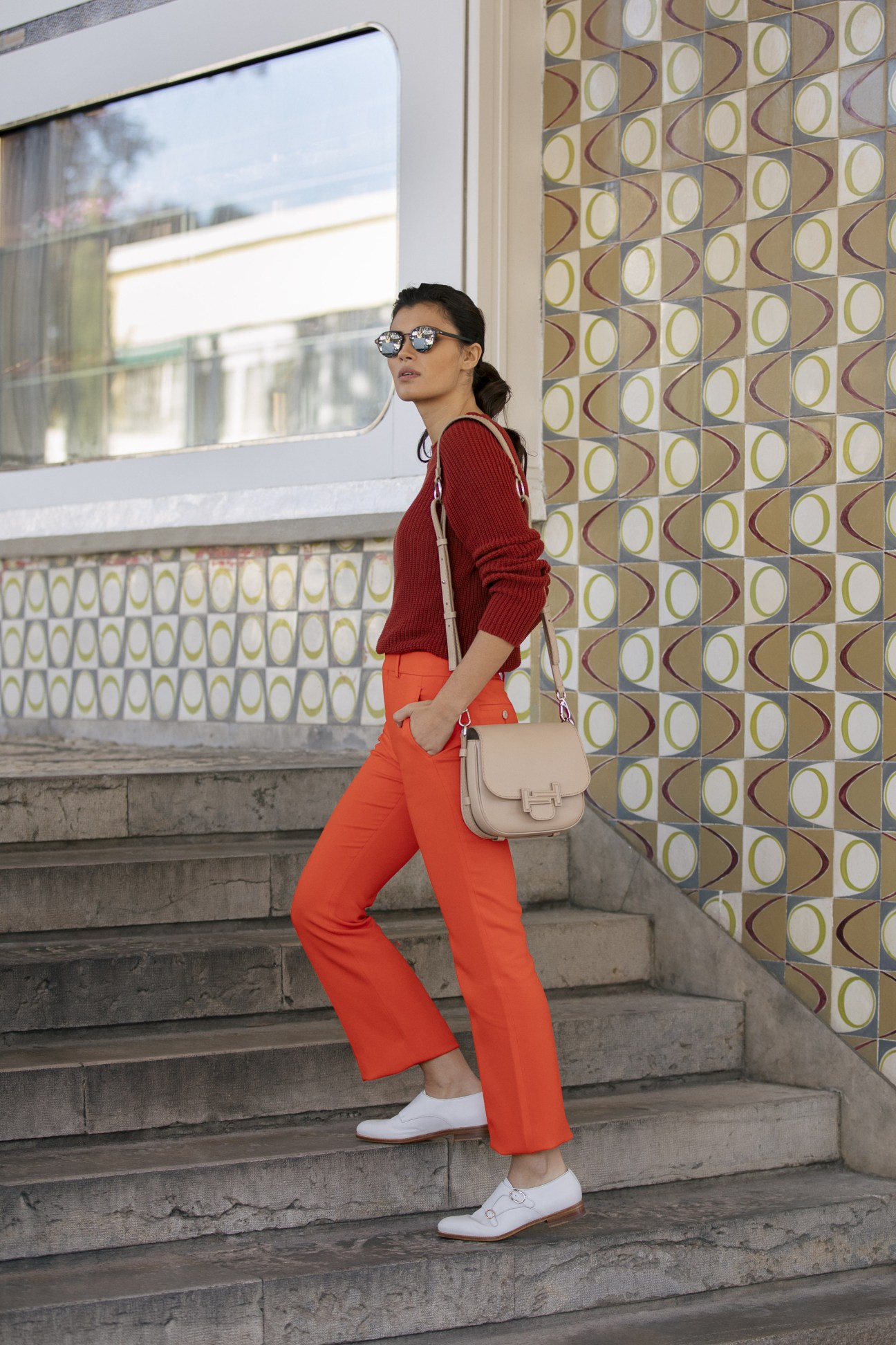 Model in Sunspel jumper with Gucci trousers and Santoni shoes, wearing Oliver Peoples sunglasses and carrying Tod's bag