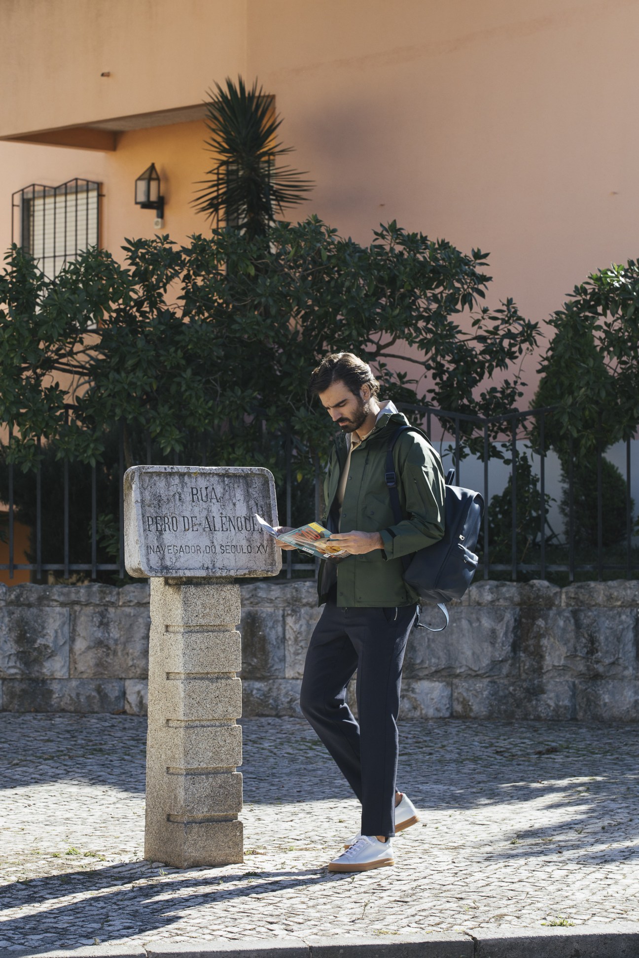 Model in Goldwin jacket with Orazio Luciano polo shirt and Emporio Armani trousers, wearing Oliver Spencer trainers and APC backpack
