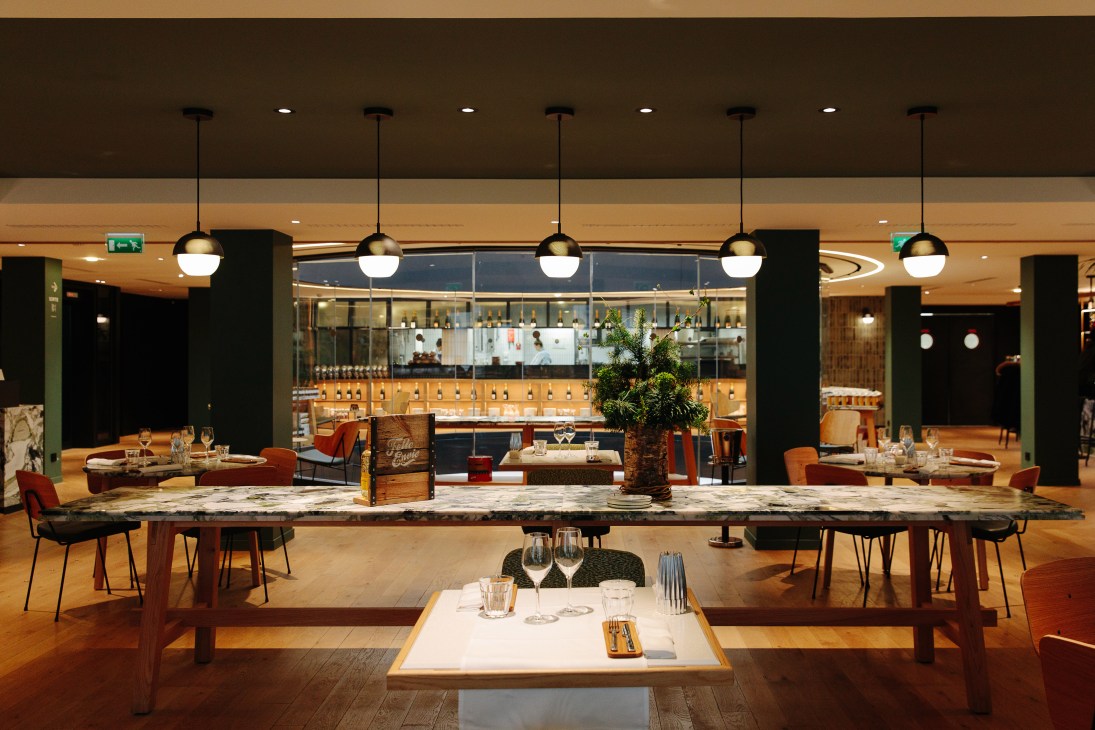 Modern restaurant dining space with marble counters, pendant lights, and open kitchen views at Grande Épicerie.