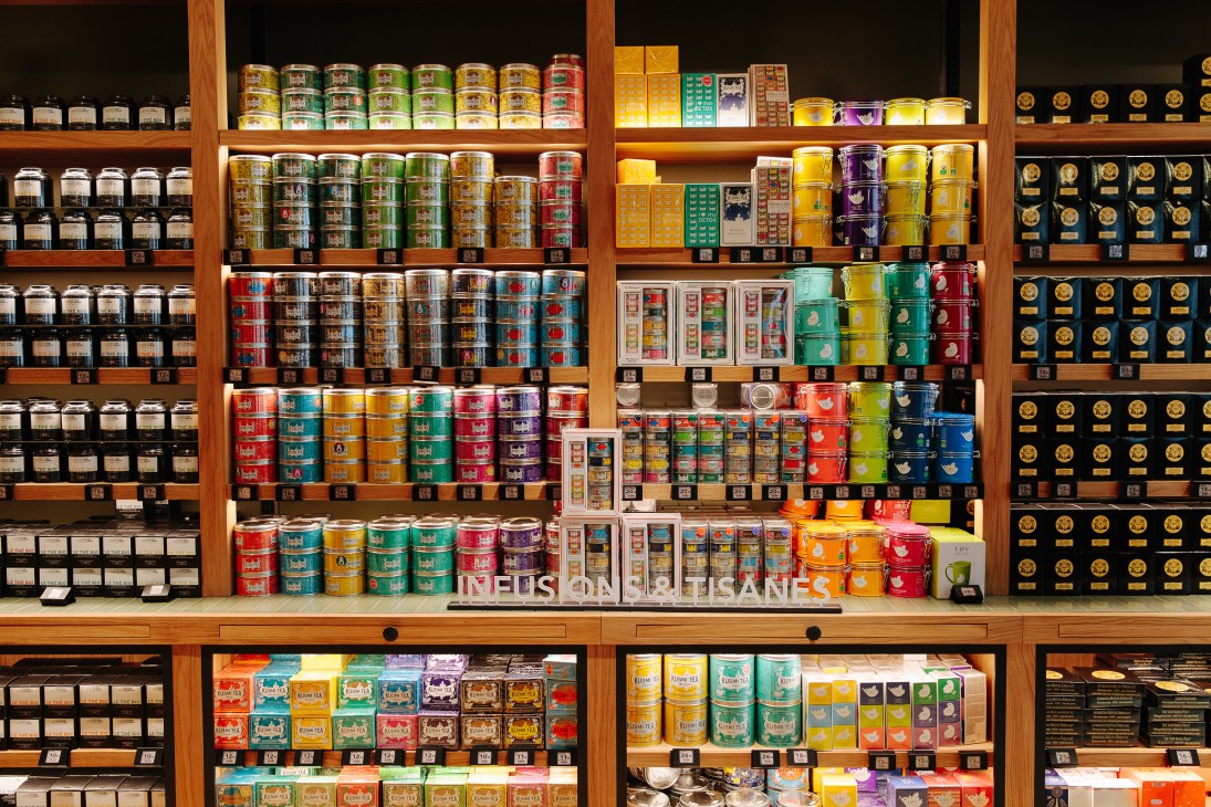 Wooden shelves displaying colorful tea tins and canisters at La Grande Épicerie.