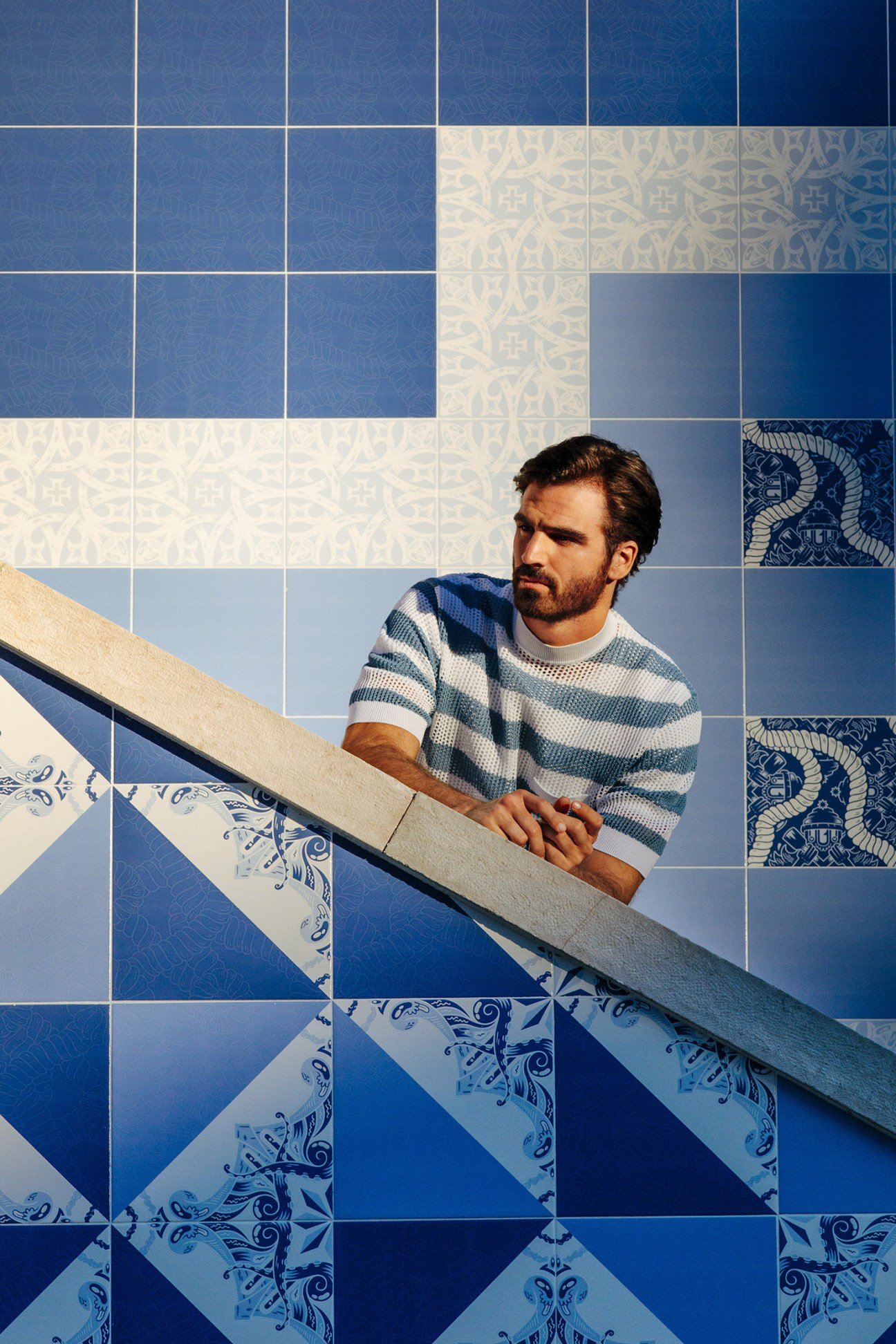 Man wearing Prada jumper and Frescobol Carioca t-shirt on blue and white tiled staircase in Lisbon.