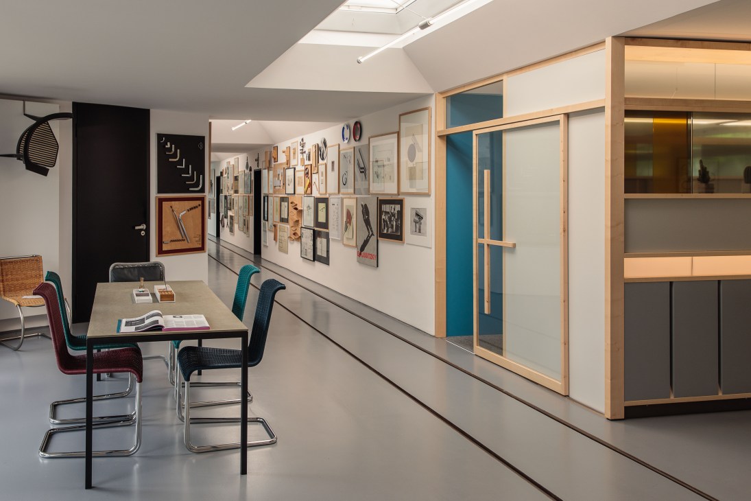 Modern office interior with cantilever chairs at table and framed design sketches on wall.