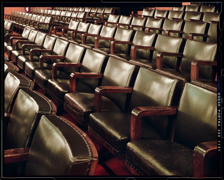 Rows of vintage leather seats with wooden armrests in an auditorium