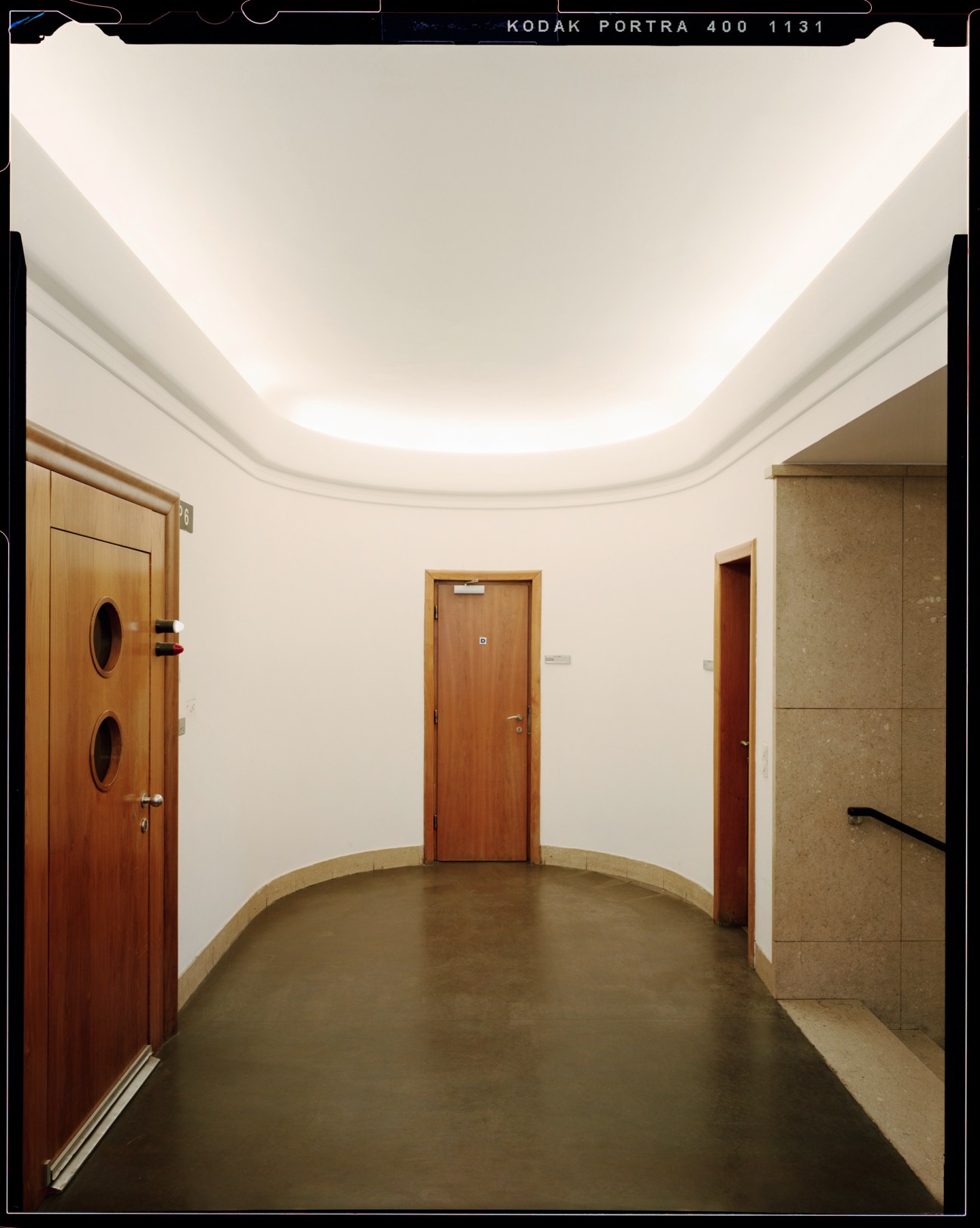 Curved white corridor with wooden doors and stone wall panels in Vienna's Funkhaus building