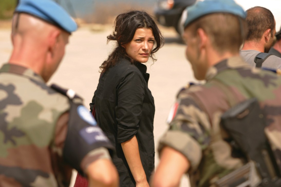 Woman in black shirt surrounded by UN peacekeepers in blue berets and military uniforms.