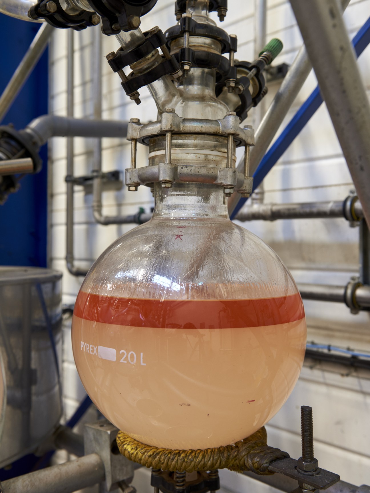 A glass Pyrex laboratory vessel containing liquid undergoing extraction in an industrial facility.
